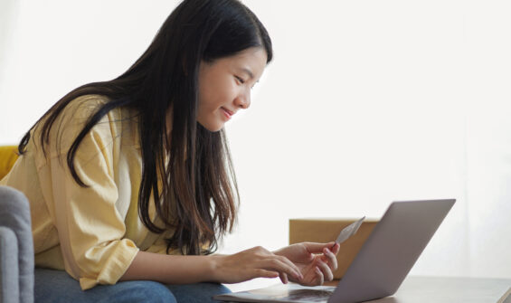 a woman using her laptop while holding a credit card