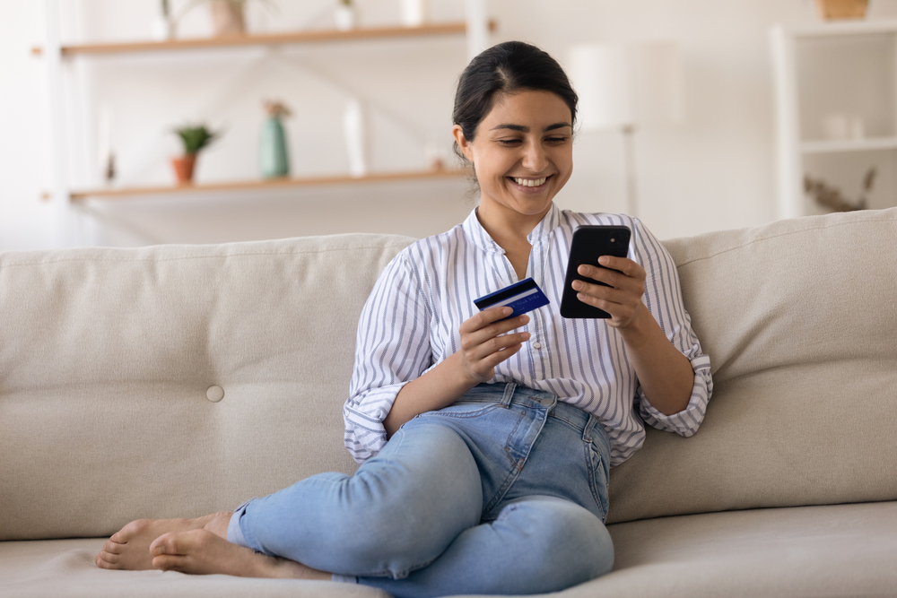 a woman using her phone and holding a credit card