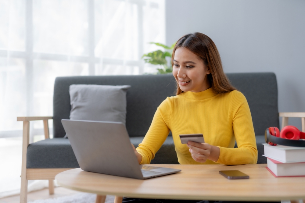 a young woman using her laptop while holding a credit card