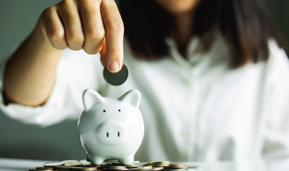 a woman putting a coin a piggy bank
